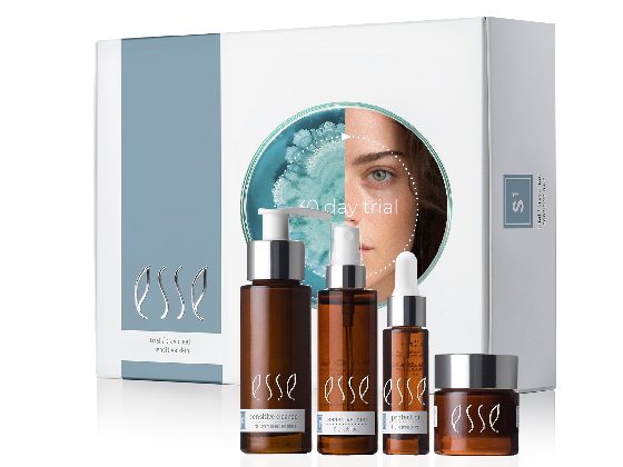 A set of Esse skincare products, including bottles with pumps, a dropper bottle, and a jar, are displayed in front of their packaging box. The box features a partially visible face and text that reads "30 day trial.
