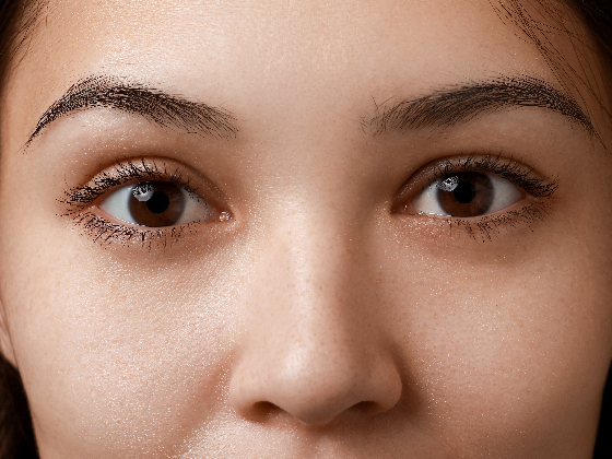 Close-up of a person's face focusing on the eyes and eyebrows, with skin that appears smooth and naturally highlighted. The well-groomed eyebrows reflect an organic elegance, much like the principles of green chemistry highlighting natural beauty.