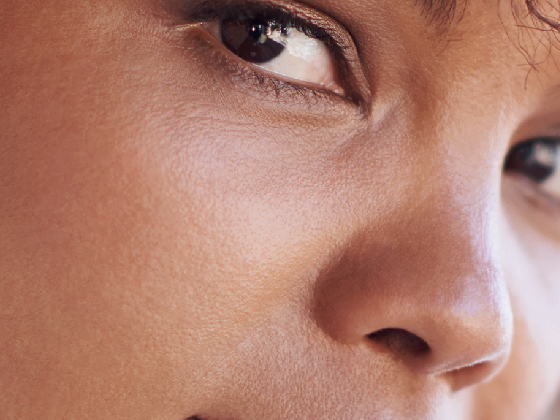 Close-up of a person's face, highlighting one eye and part of the nose and cheek, with smooth skin and natural makeup achieved through green chemistry principles.
