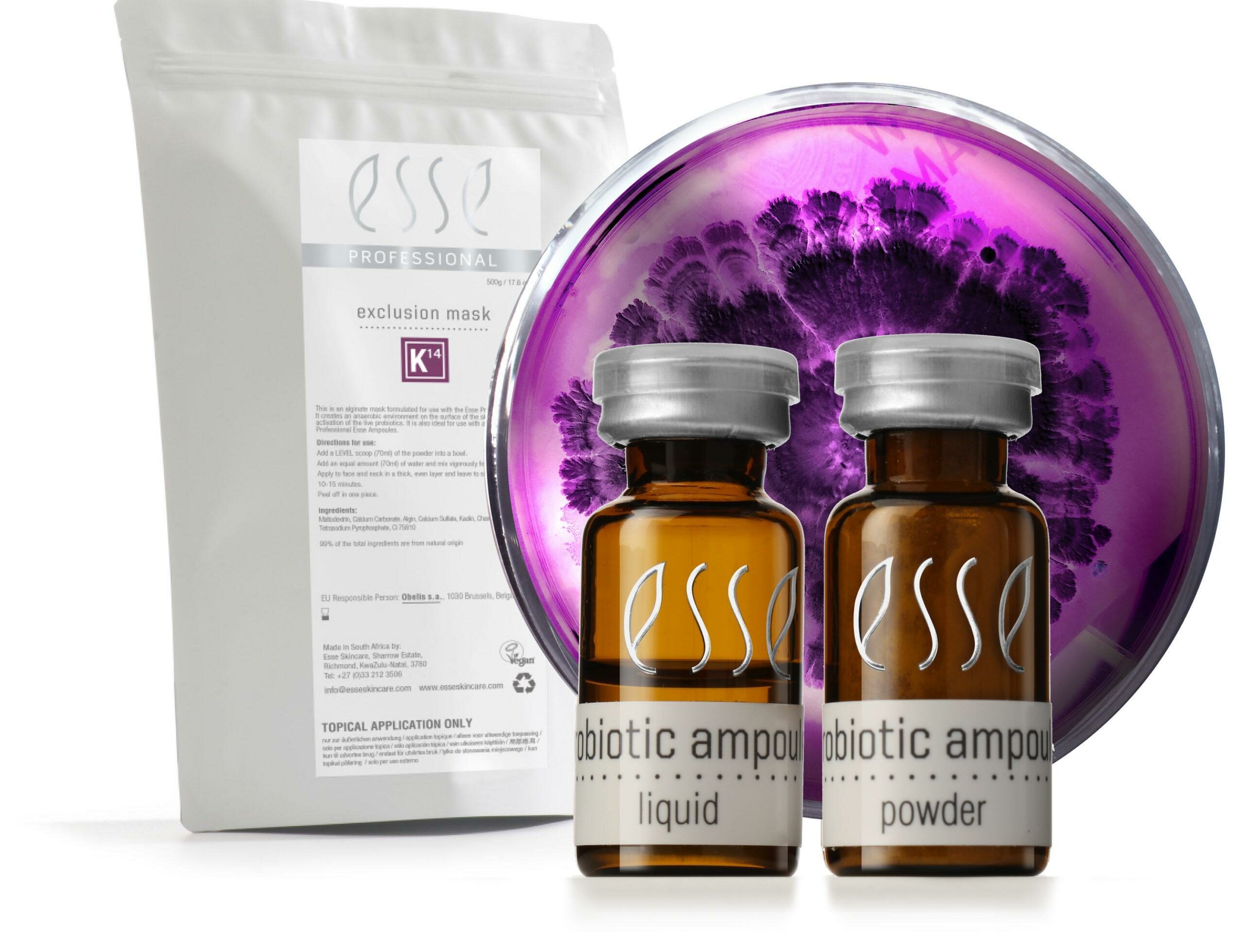 Packshot_Microbes A product set featuring a white packet labeled "exclusion mask" beside two brown bottles labeled "probiotic ampoule" with "liquid" and "powder" respectively. Behind them is a petri dish with a purple culture. The brand name "Esse" is displayed on all items.