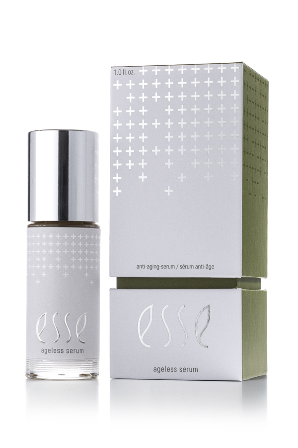 A bottle of Esse Ageless Serum with a silver cap sits beside its matching silver and green box, both featuring a minimalist design with small plus signs and the product name.
