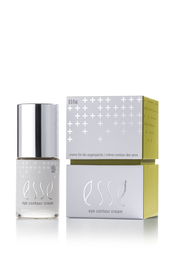 A bottle of Esse Eye Contour Cream with a silver cap sits beside its white and green box, both showcasing a minimalist design with plus signs and product details.