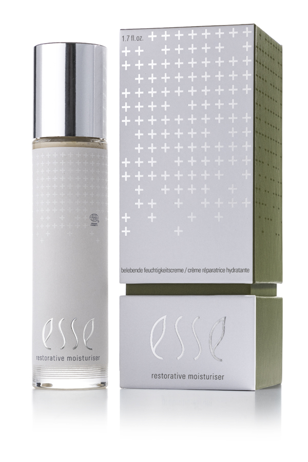A bottle of Esse Restorative Moisturiser with a silver cap is placed beside its matching box, which features a silver and green design with plus signs and product details.