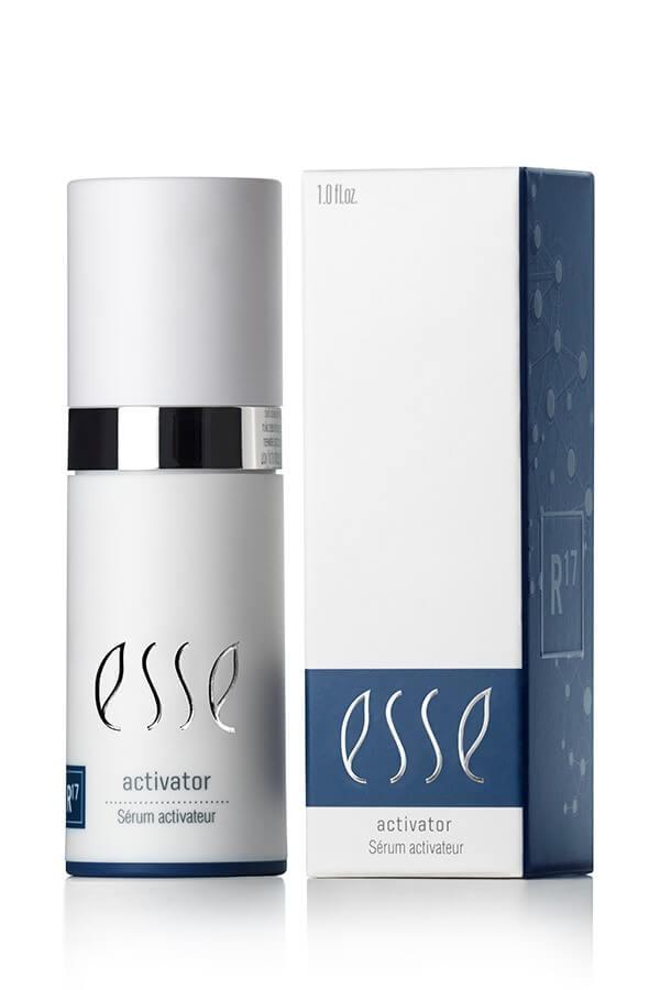 A 1.0 fl.oz. bottle of Esse Activator, elegantly designed with a silver accent, is displayed next to its matching white and blue box packaging featuring the same branding and the text "R17" on the side.