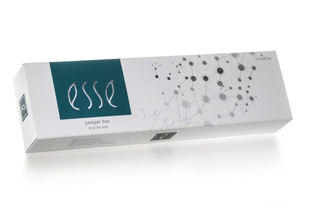 A white and teal box labeled "Esse Limited Edition Festive Pamper Box, for all skin types." The box also displays molecular graphic designs and indicates a weight of 4 x 0.34 fl oz. The logo and text are stylishly presented against a clean, modern background.