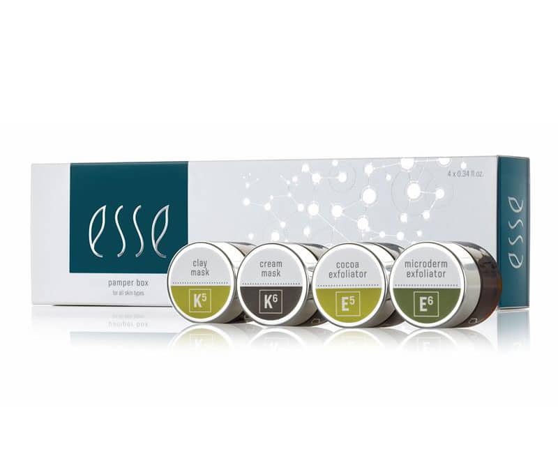 A box of Esse skincare products with four small jars displayed in front. The jars are labeled as clay mask (K5), cream mask (K6), cocoa exfoliator (E5), and microderm exfoliator (E6). The packaging is white with green and black accents.